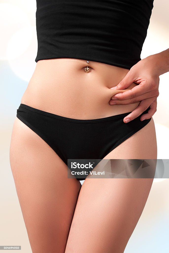 belly fat calories diet Woman`s slim figure in black underwear. Holding abdomen fat, isolated with work path. Adipose Cell Stock Photo