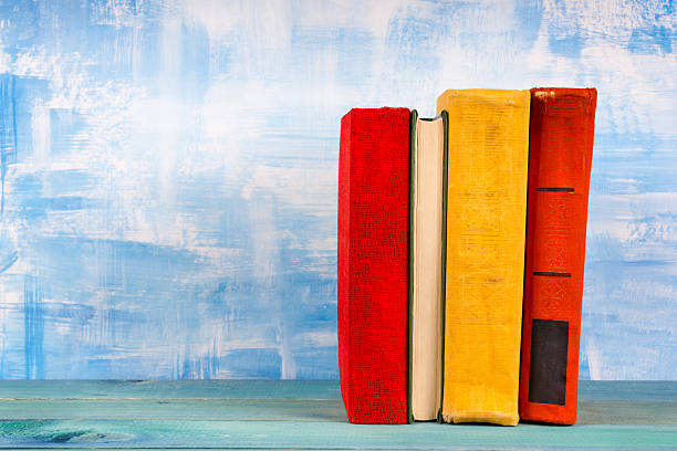 istock Stack of colorful hardback books, open book on blue background 504694296