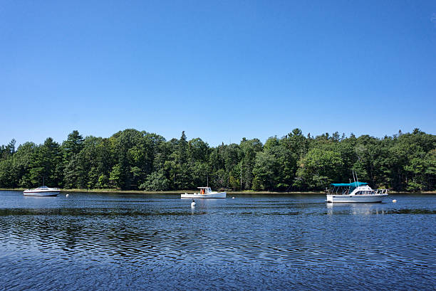 Three boats moored on Union River at Ellsworth Maine in the summertime.