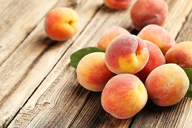 istock Ripe peaches fruit on a brown wooden background 504698744