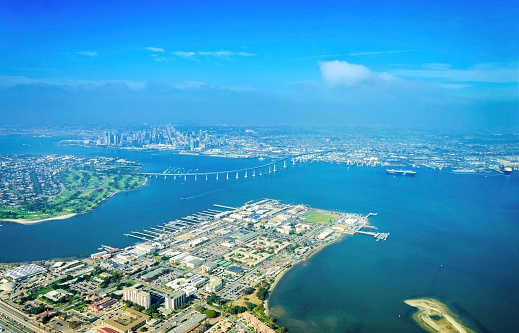 Aerial view of the Coronado island and bridge in the San Diego Bay in Southern California, United States of America. A view of the Skyline of the city and some boats crossing the the sea.