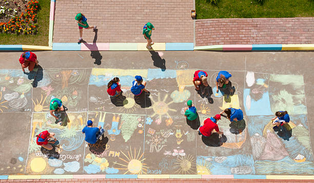 Overhead view of children drawing chalk pictures stock photo