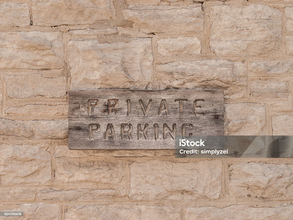 Private Parking Private Parking sign carved in weathered wood sign mounted on grey cement brick wall. Brick Stock Photo