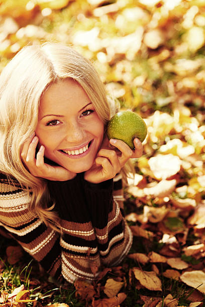 woman eat apple in autumn park