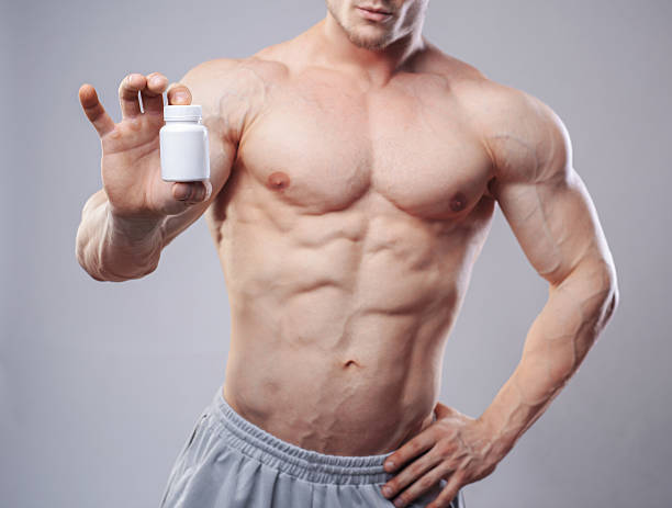 blanco bodybuilder con un recipiente de píldoras en neitral fondo - esteroides fotografías e imágenes de stock
