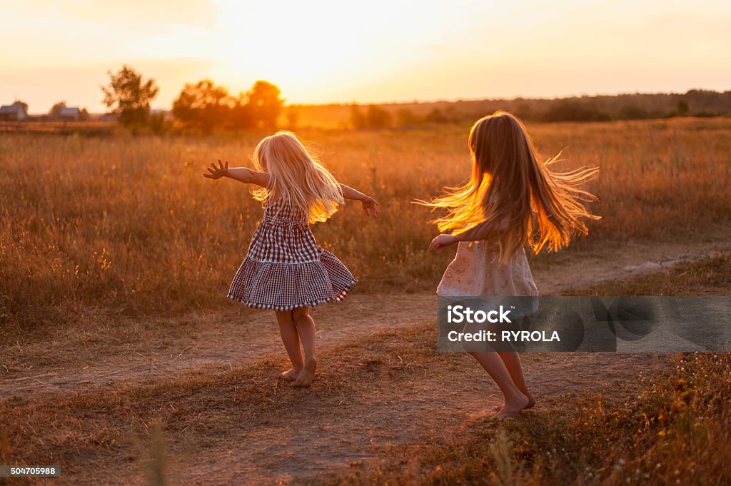 Dos Chicas bailando en un campo al atardecer - Foto de stock de Hijos libre de derechos