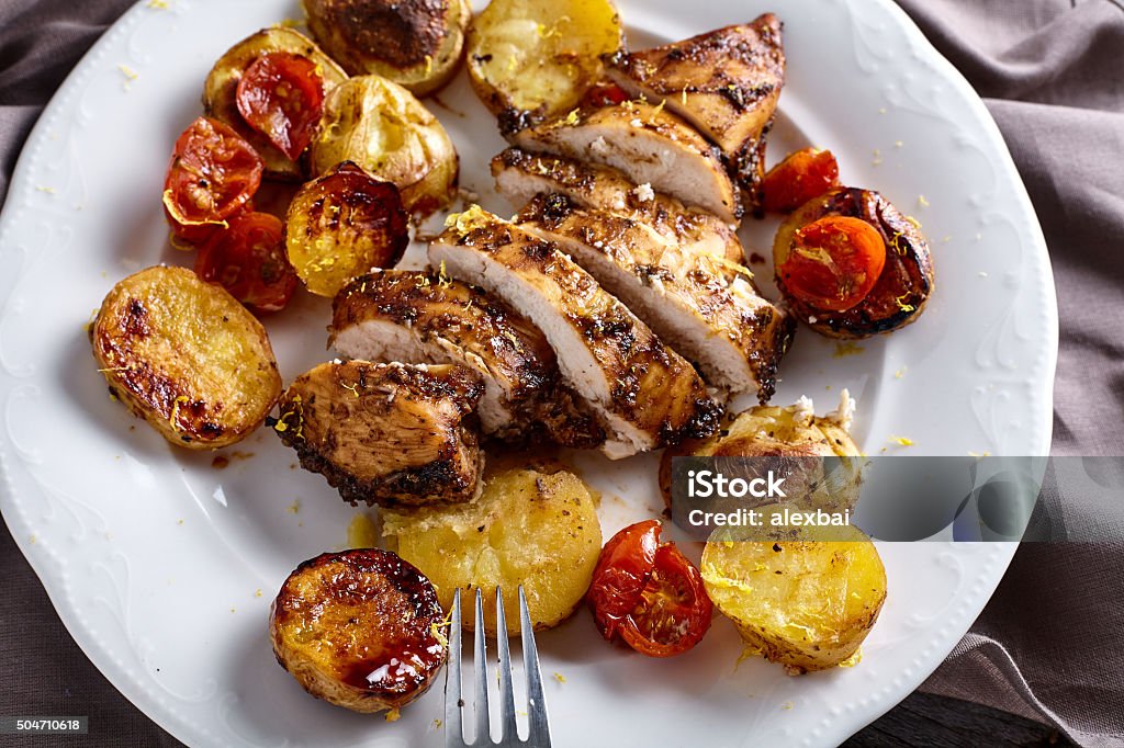 Roasted chicken breast with vegetables Roasted chicken breast in honey-balsamic marinade with potatoes and cherry tomatoes on white plate Appetizer Stock Photo