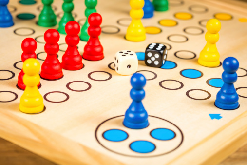 Details of a ludo board game being played outdoors