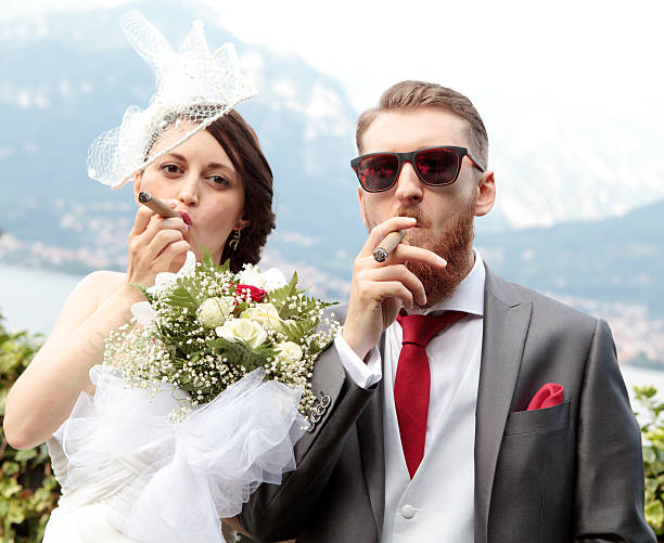 Bride and groom smoking a cigar stock photo