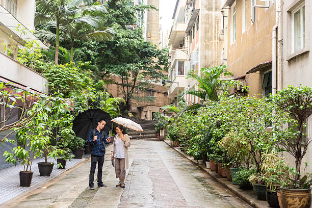 Asian Mother and Son Viewing Mobile Phone in Residential Area Asian mother and son looking at smart phone, surrounded by apartment buildings in the affluent Mid-Levels residential area of Hong Kong. tourist couple candid travel stock pictures, royalty-free photos & images