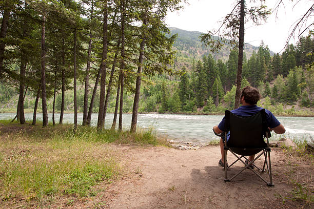 homme relaxant au bord de la rivière - flathead national forest photos et images de collection