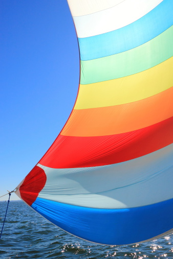 The wind has filled the spinnaker on sailing yacht. Detail of a colorful sail against the deep blue sky.