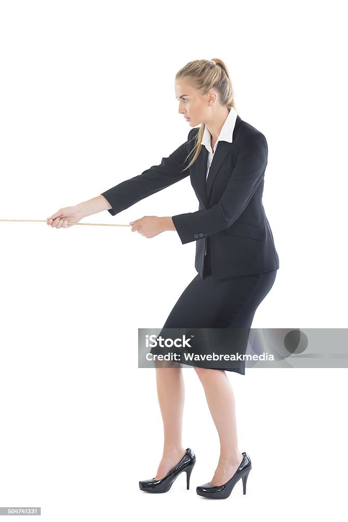 Focused blonde businesswoman pulling a rope Focused blonde businesswoman pulling a rope on white background Tug-of-war Stock Photo