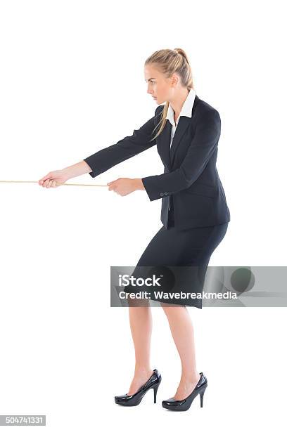 Focused Blonde Businesswoman Pulling A Rope Stock Photo - Download Image Now - Tug-of-war, White Background, 20-29 Years