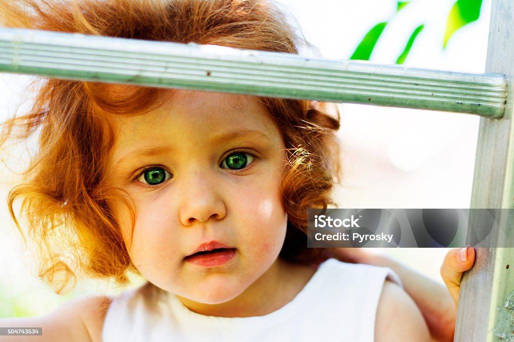 Little redhead girl looking straight to you. Little redhead girl with green eyes looking at you. 12-17 Months Stock Photo