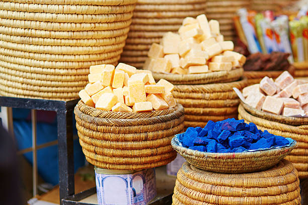 Traditional Moroccan bazaar displaying colorful spices and herbs in ornate, gold-detailed containers on a rustic wooden shelf