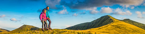 istock Young hikers on green mountain ridge watching wilderness sunset panorama 504744244