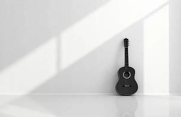 Photo of Black acoustic guitar in a white room