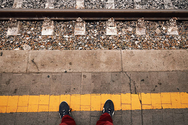 POV standing at the yellow line of railway platform stock photo