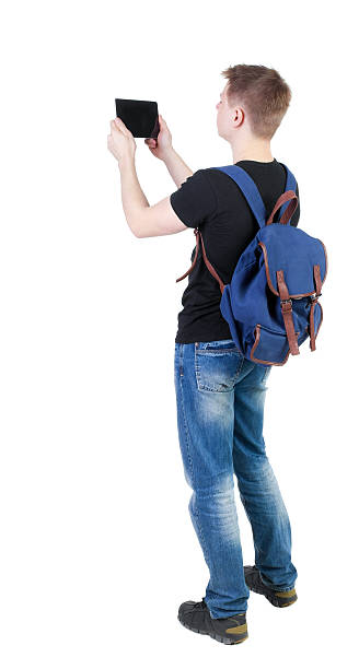 vista traseira do jovem homem de pé com tablet computador - travel ipad isolated backpack - fotografias e filmes do acervo