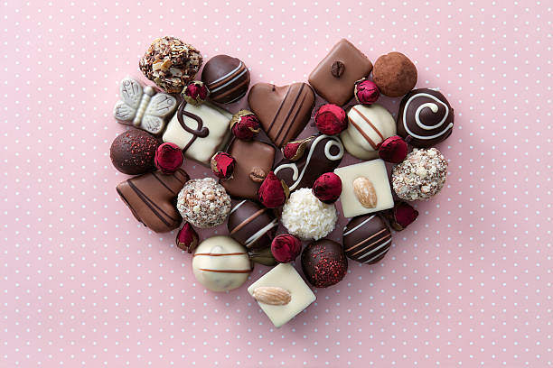Chocolate candies heart Chocolate candies and dried rose flowers heart shape composition. Sweet gift of love for St. Valentines Day. heart shape valentines day chocolate candy food stock pictures, royalty-free photos & images