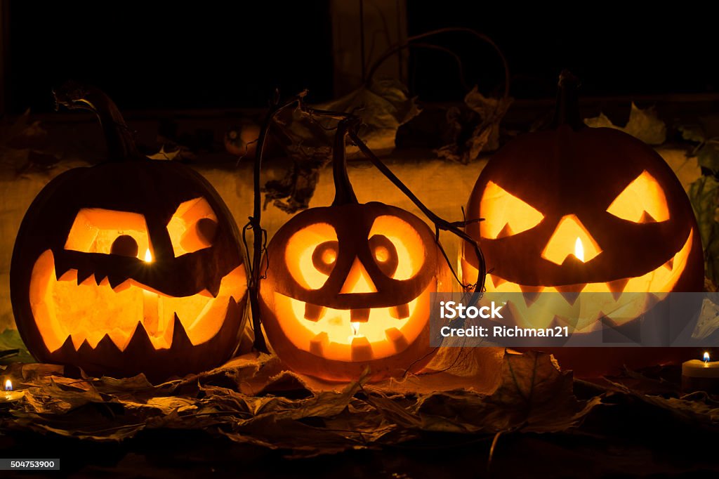 Photo of three pumpkins for Halloween. Photo of three pumpkins for Halloween. Embittered, cheerful with a smile and evil pumpkin against autumn leaves and candles Autumn Stock Photo