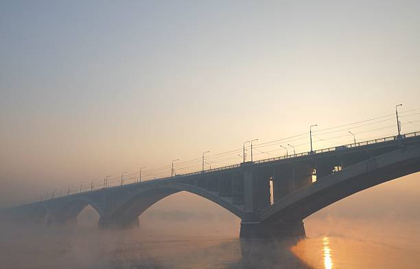 Communal Bridge at sunset in the mist over the river Communal Bridge at sunset in the mist over the river krasnoyarsk krai photos stock pictures, royalty-free photos & images