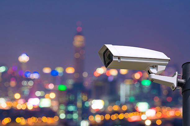 istock Single CCTV Security camera on Blurred night downtown city, buil 504758894