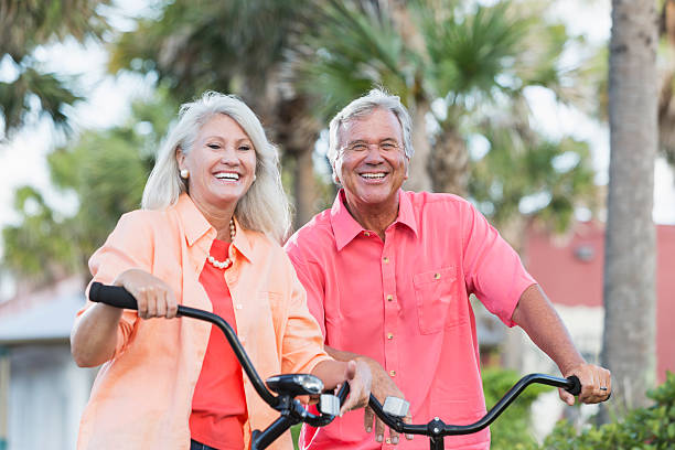 bicicletas de equitação casal de férias - action mature adult bicycle senior couple imagens e fotografias de stock