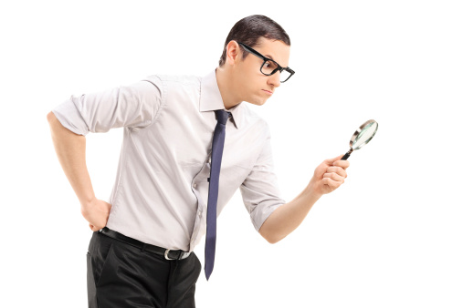 Serious man looking through a magnifying glass isolated against  white background