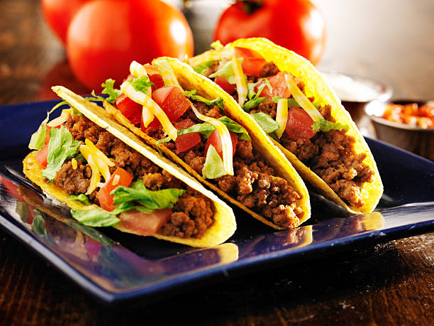 istock three beef tacos with cheese, lettuce and tomatos 504782727