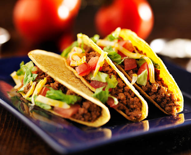 istock three beef hard shell tacos with cheese, lettuce and tomatoes 504782729