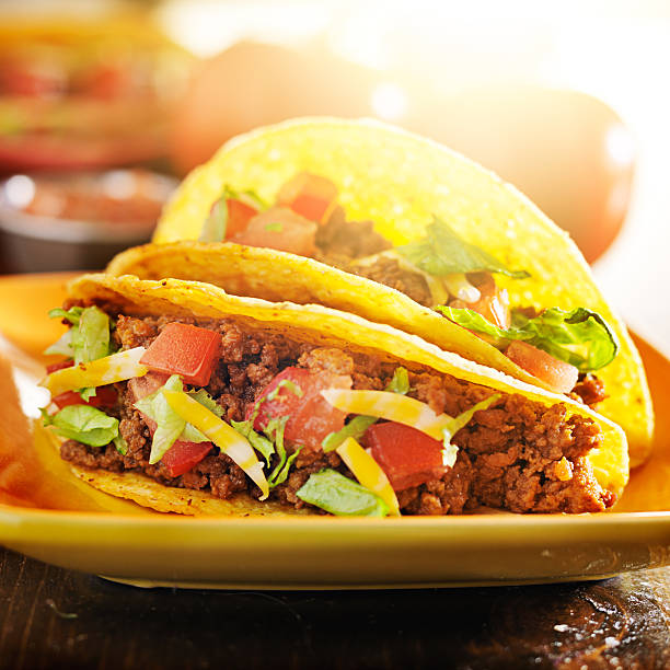 istock two beef hard tacos with cheese, lettuce and tomatoes 504782733