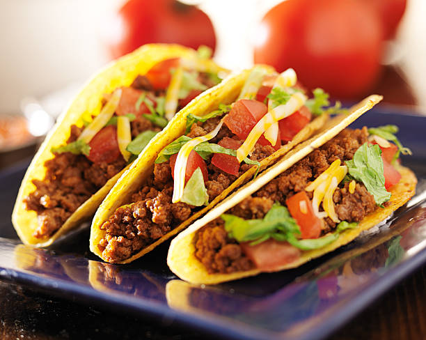 three beef hars shell tacos with cheese, lettuce and tomatoes