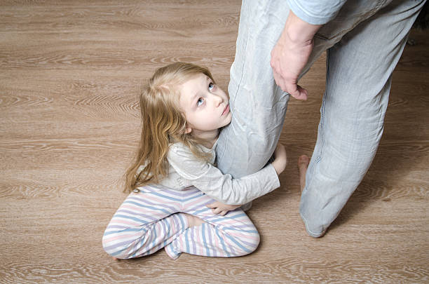 Young girl hugging her father's leg Sad little girl sitting on the floor and hugging her father's leg, top view pleading stock pictures, royalty-free photos & images
