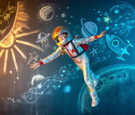 Happy girl astronaut flying free in outer space. The illusion of flight on a background of the space drawing in chalk