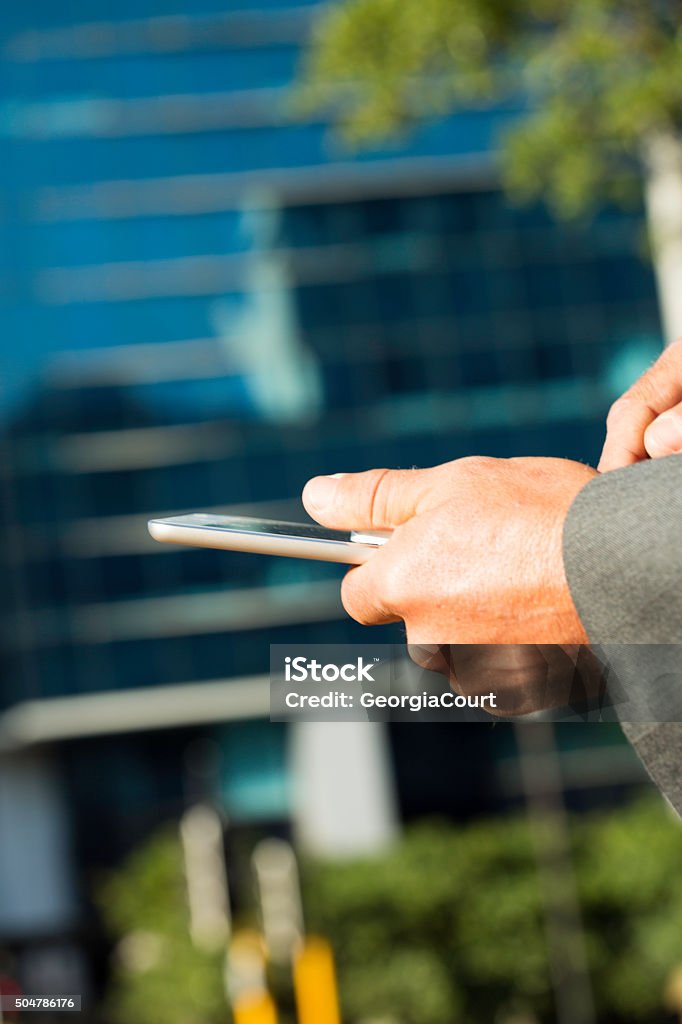 Businessman ordering uber taxi on smart phone Close up of a businessman's hands as he orders a uber taxi on his smart phone. Adult Stock Photo