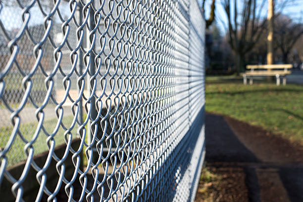 metal fence cage closeup in a park metal fence cage in a soccer field, park bench behind, sunny day, closeup, detail, horizontal wire mesh stock pictures, royalty-free photos & images