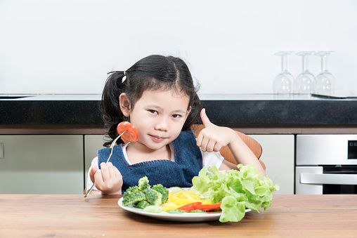 Little asian girl with vegetables food