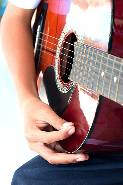 istock blurred boy's hands playing old acoustic guitar, 504787574