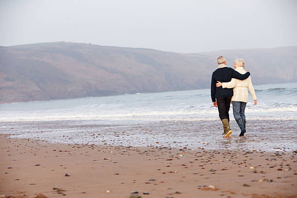 istock Senior Couple Walking Along Winter Beach 504787713