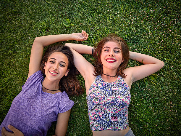 Teenage girls laying in grass