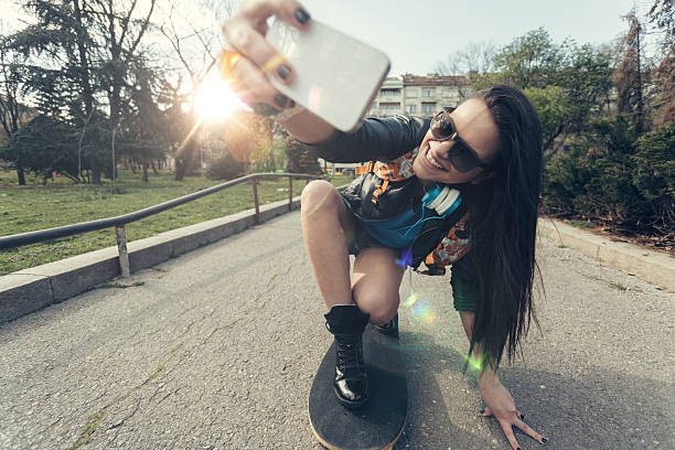 Teenage girl taking a selfie at a skateboard Young girl skateboarding in the park longboarding stock pictures, royalty-free photos & images