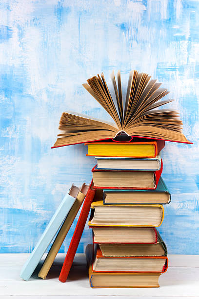 istock Stack of colorful hardback books, open book on blue background 504816818
