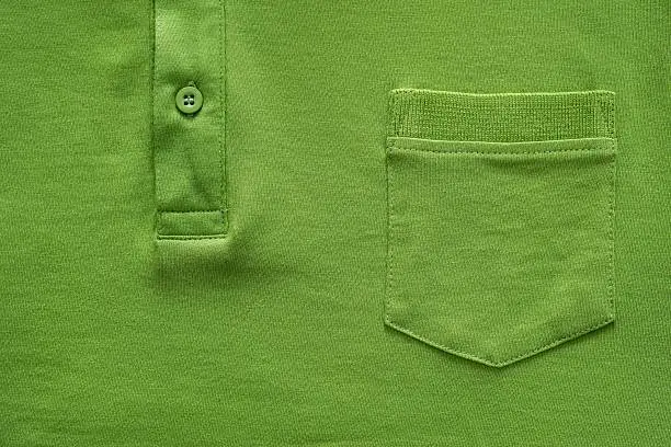 closeup part of a shirt from cotton fabric of green color with a big pocket and a fastener with the button
