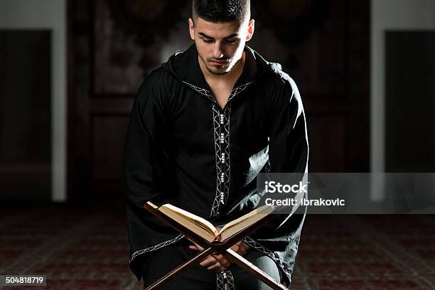 Hombre Musulmana En Dishdasha Se Lee Quran Foto de stock y más banco de imágenes de Adulto joven - Adulto joven, Corán, Leer