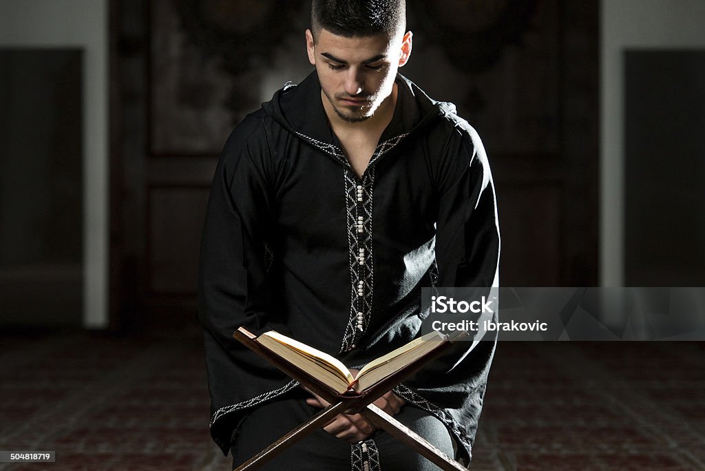Homem muçulmano é o Dishdasha leitura do Alcorão - Foto de stock de Alcorão royalty-free