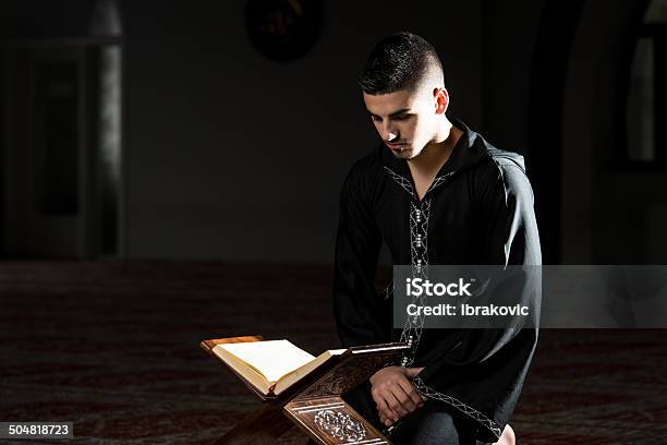 Uomo Di Musulmana Leggendo Il Corano Dishdasha È - Fotografie stock e altre immagini di Abbigliamento - Abbigliamento, Adulto, Ambientazione interna