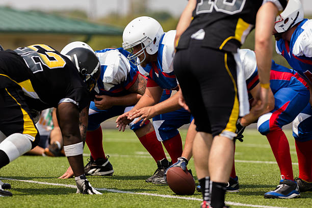 Sports: Football teams prepare for a play.  Line of scrimmage. Center prepares to hike the football to the quarterback. Line of scrimmage.  offensive line stock pictures, royalty-free photos & images
