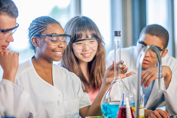 Holding a Test Tube A multi-ethnic group of college students are working on a science experiment in the chemistry lab. The students are observing the liquid solution in the beaker. secondary school activities stock pictures, royalty-free photos & images